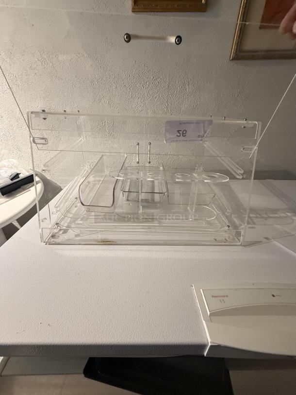 Clear acrylic display case, 21" wide, features removable dividers for custom organization. Transparent design ensures product visibility.