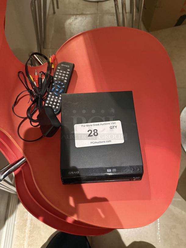 Craig Compact DVD/CD Player with remote and RCA cables on a red chair, tagged for auction as item 28.