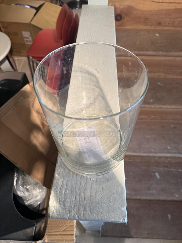 Large clear glass cylinder vase, versatile for decor or storage. Features classic straight-sided design. Slight wear visible.