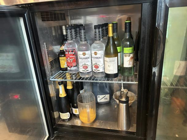 Migali BB60-N12 back bar refrigerator, like new condition, with two glass doors, stocked with assorted bottles, tested and working.