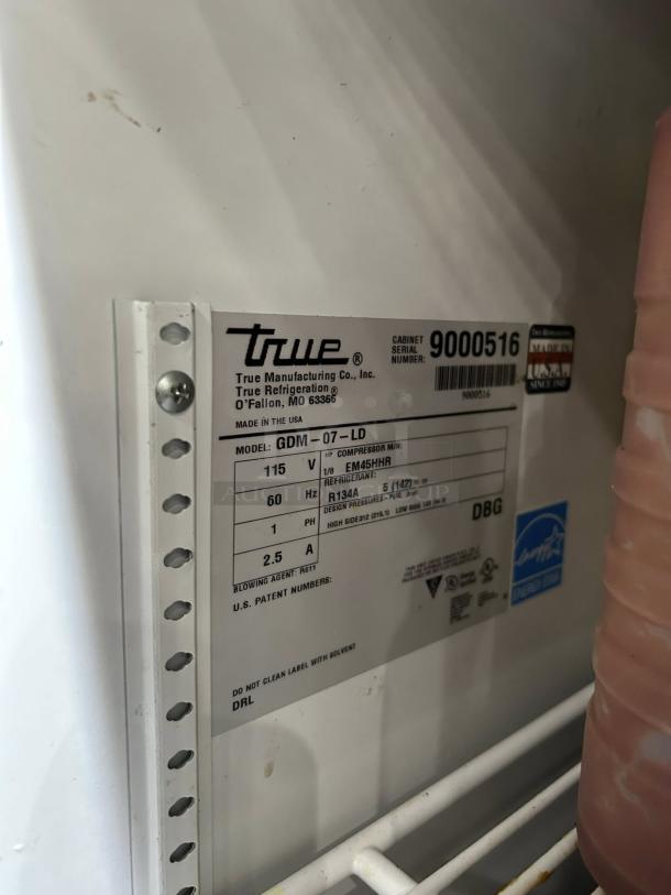 True GDM-07 tag on black refrigerated glass door merchandiser. Model info: 115V, R134A refrigerant, 2.5A. Made in USA.