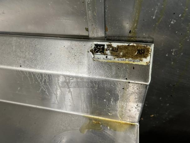 John Boos stainless steel worktable, model ST6R5-3060GBK, with visible label and NSF marking, showing some wear.