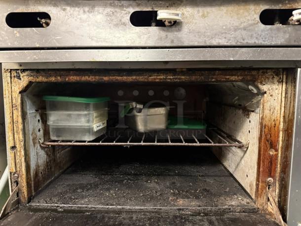 Wolf C36S-36G 36" gas range oven interior, with visible wear. Includes a shelf with plastic containers inside.