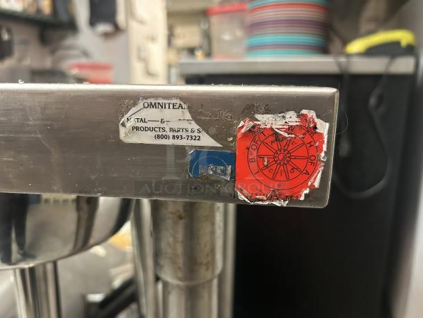 Omniteam stainless steel work table, 24"x24", excellent condition, with casters. Features visible labels with contact info.