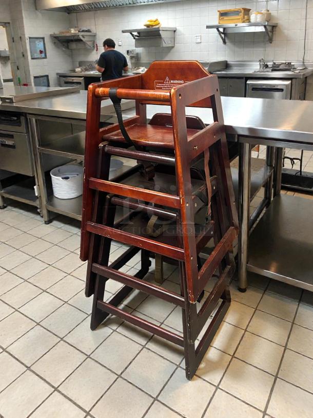 Modesto brown wood high chair in excellent condition, sturdy build, visible safety warning label, in a kitchen setting.