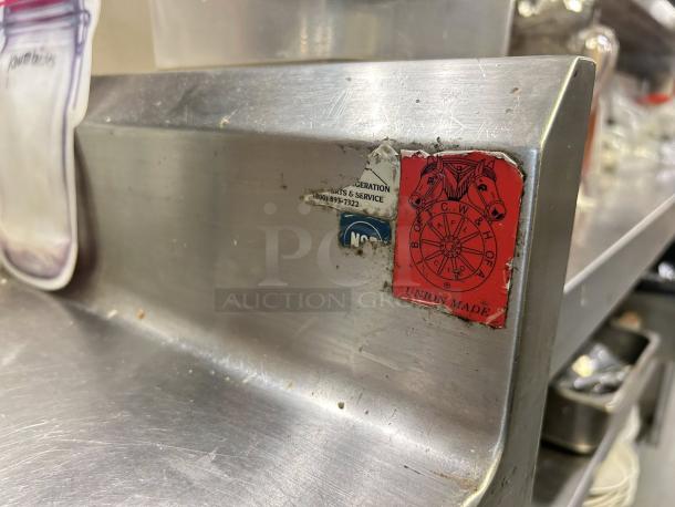 Omniteam stainless steel worktable with backsplash, size 24” x 35”. Features red "Union Made" label. Sturdy condition.