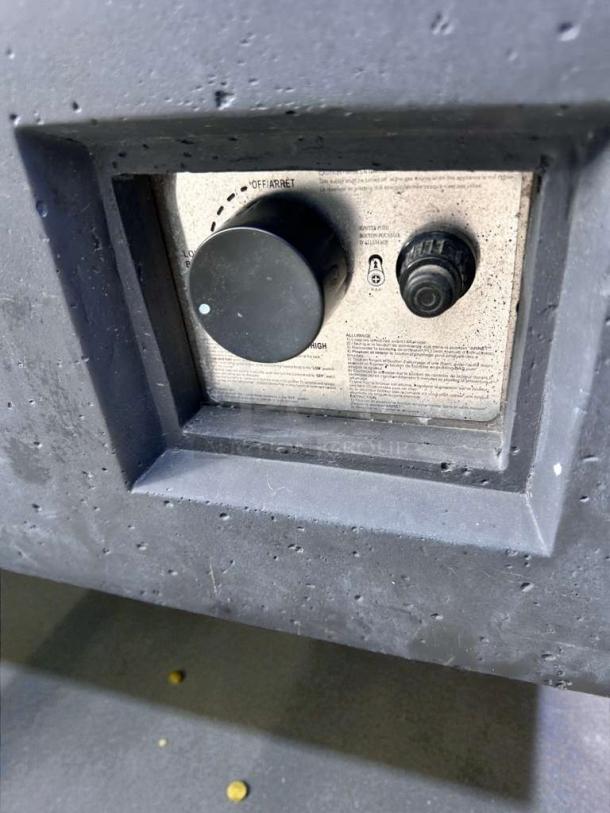 Outdoor gas fire pit table control panel in pristine condition; visible dial for adjusting flame and ignition switch.