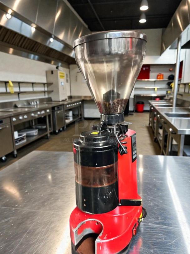 Red commercial coffee grinder in premium condition, 120V, fully tested and working, placed on a metal countertop in a kitchen setting.