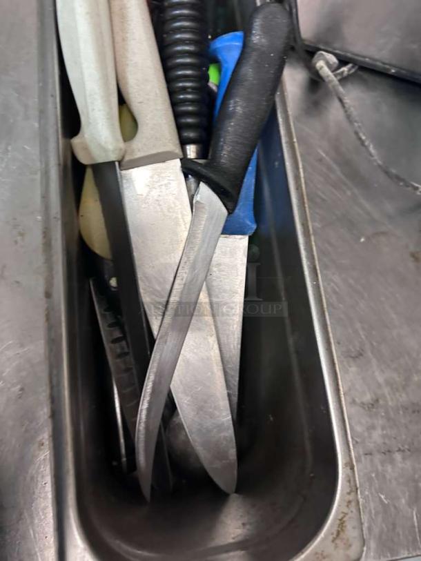 Assorted commercial kitchen knives in a metal tray, premium condition, various brands, inspected and ready for use.