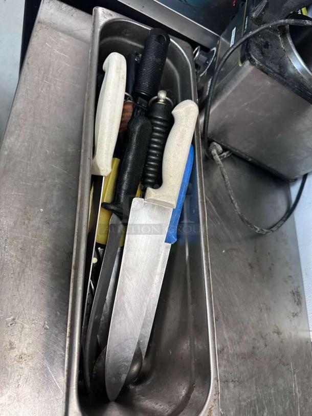 Assorted commercial kitchen knives in premium condition, various brands, fully inspected, ready for use, stored in a metal holder.