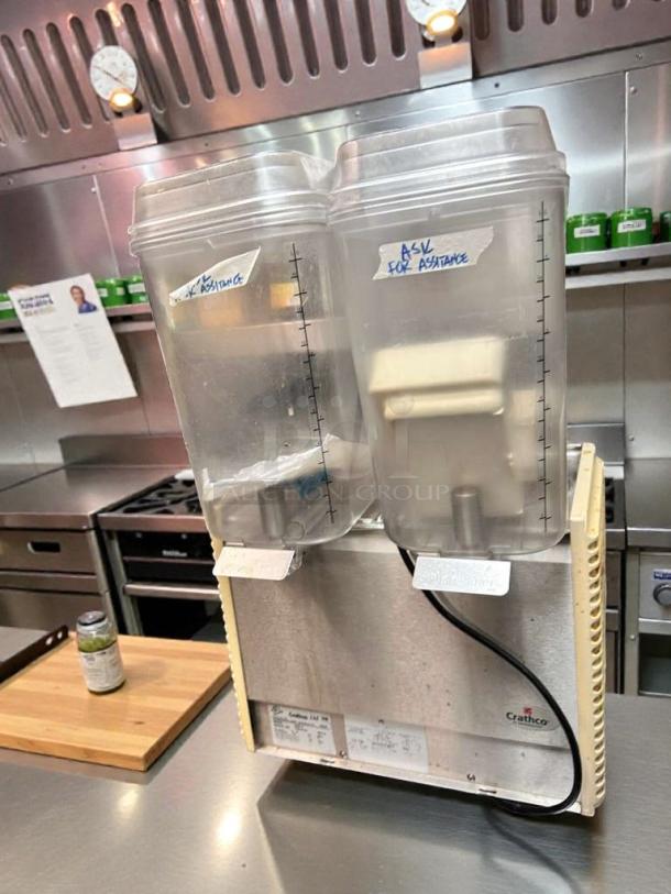 Crathco D25-4 dual frozen beverage dispenser, outstanding condition, 115V, fully tested. Dual clear containers with volume markings.