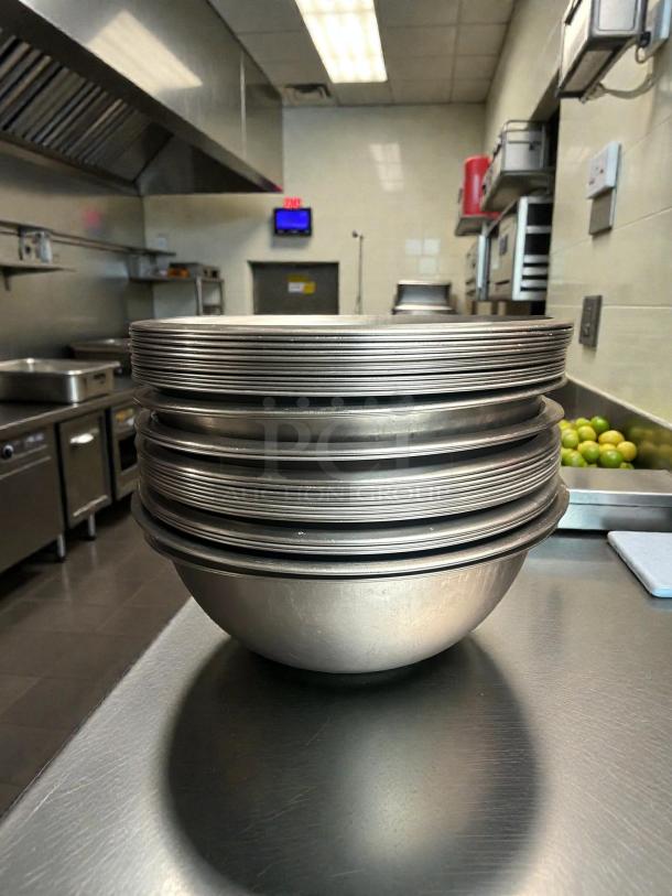 Browne 10 1/2" stainless steel mixing bowl in good condition, shown on a kitchen counter with stacked plates.