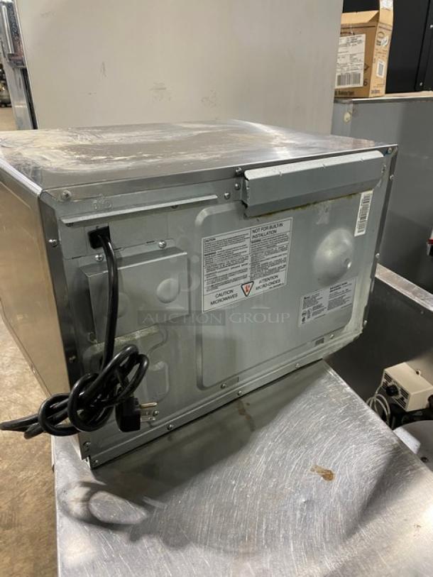 Amana RFS12SW2A stainless steel commercial countertop microwave, electric-powered, digital control, visible cord and labels, model and serial number displayed, used condition.
