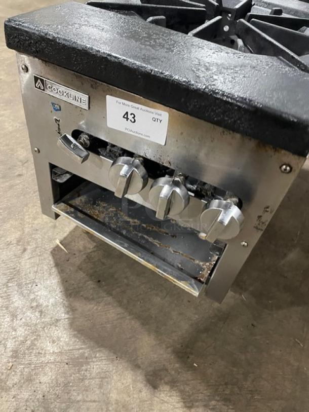 Cookline commercial stainless steel double burner stock pot range, gas-powered, on legs. Features control knobs and visible Cookline branding.