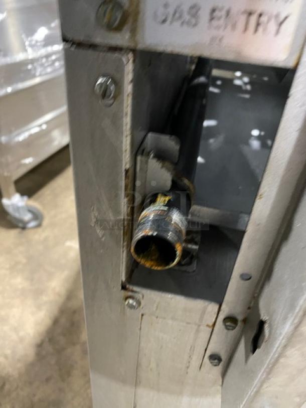 Qualite stainless steel gas range/oven combo, six burners, with backsplash, overhead salamander shelf, and wired oven rack.