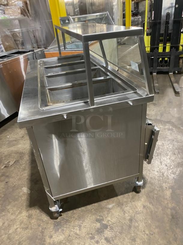 Atlas Metal WIHD&M4 stainless steel 4 well hot food table, electric powered, with sneeze guard, 208V, on casters.