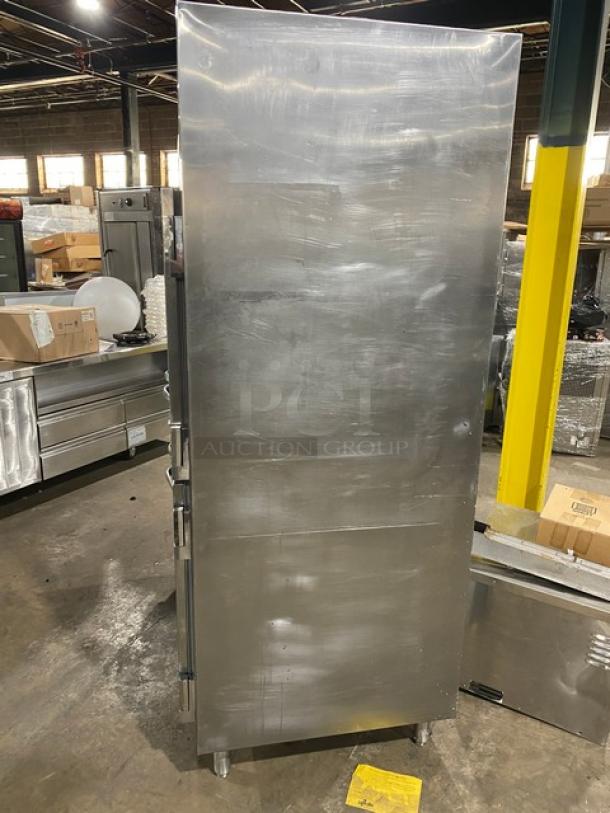 Traulsen commercial stainless steel 4 half-door double section reach-in refrigerator, with built-in pan slides, displayed in a warehouse, on legs.