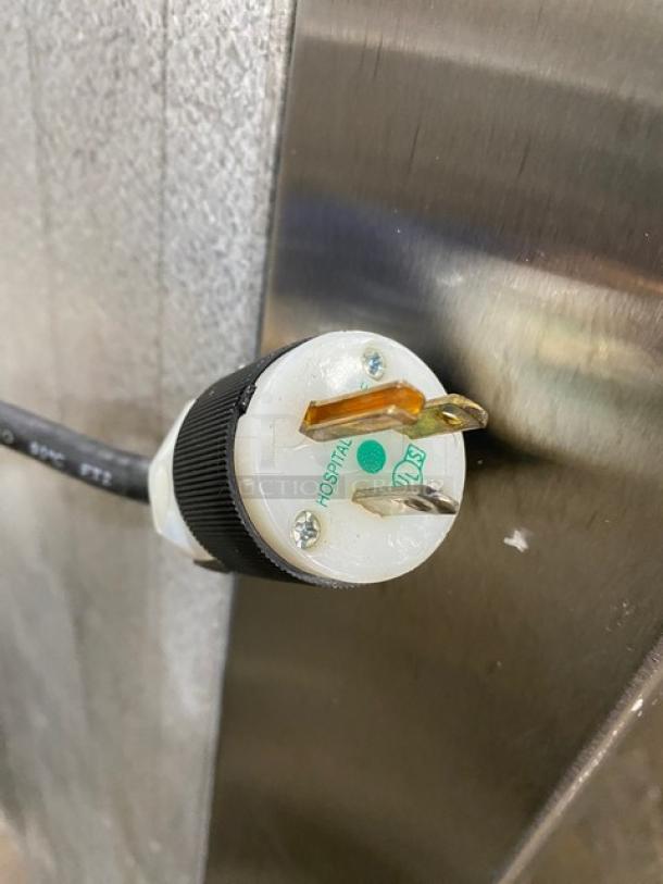 Traulsen Commercial Stainless Steel Refrigerator, 4 half-doors, double section, built-in pan slides, on legs. Markings: power plug close-up.