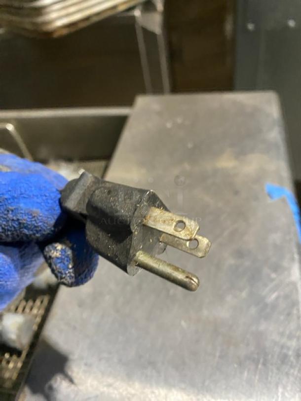 Close-up of a plug held with a gloved hand, likely from a Pitco SELVBNB fryer; no item features visible.