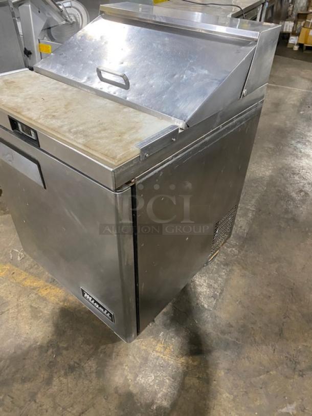 Migali stainless steel refrigerated bain-marie prep table with cutting board and poly-coated rack, on casters.