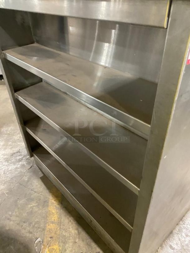 Commercial stainless steel multi-tier dry worktop table with back splash and rear shelving. Enclosed cabinet style.