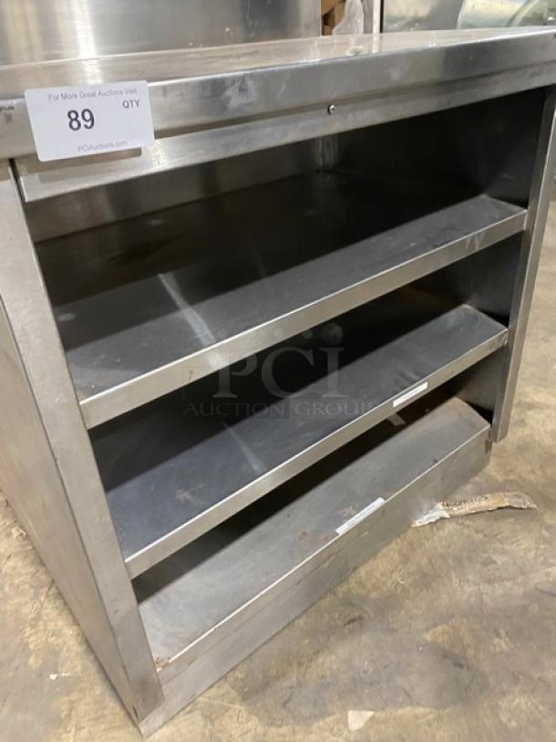Commercial stainless steel enclosed cabinet with multi-tier shelves, backsplash, and rear shelving. Item 89, durable condition.