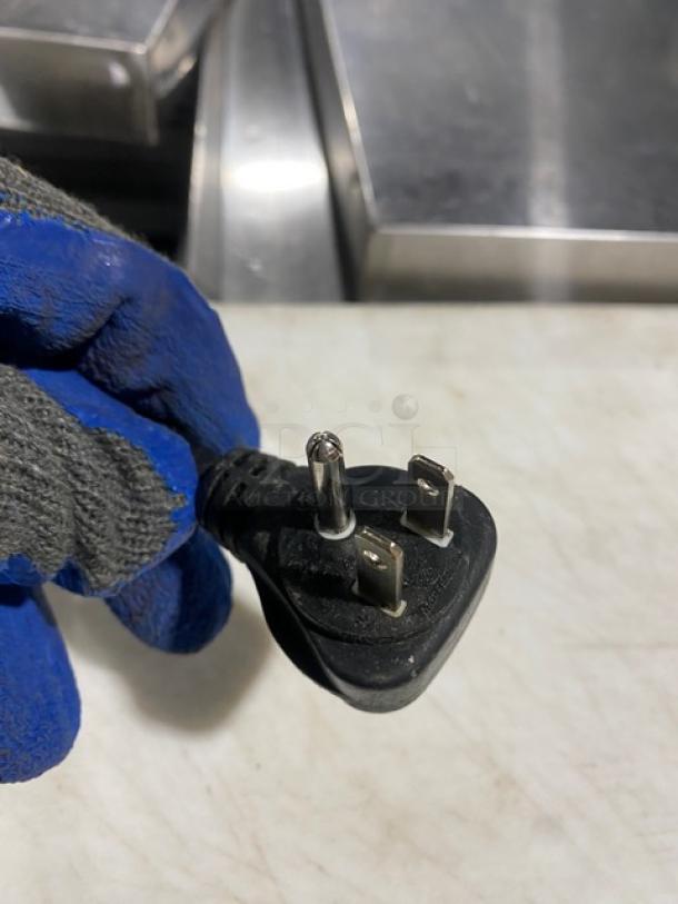 A power plug is shown with a gloved hand in the background.