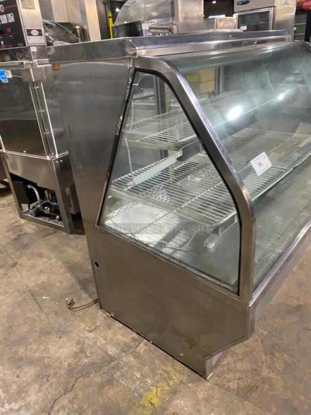 Stainless steel slanted glass bakery display case with poly-coated wire racks and rear double sliding glass doors; excellent condition.
