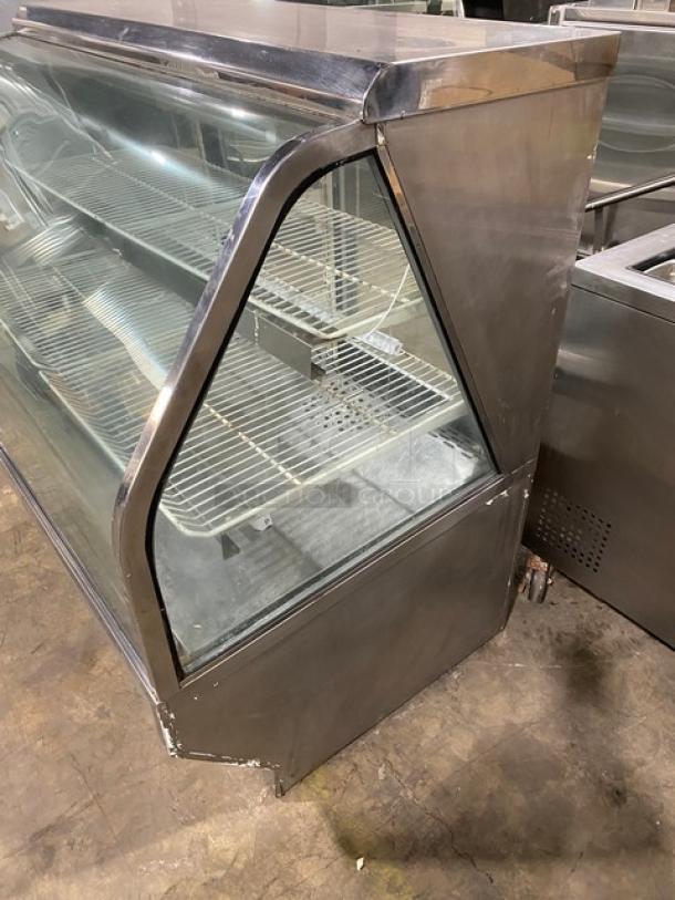 Commercial stainless steel bakery display case with slanted glass, multi-tier poly-coated wire racks, and rear sliding doors.