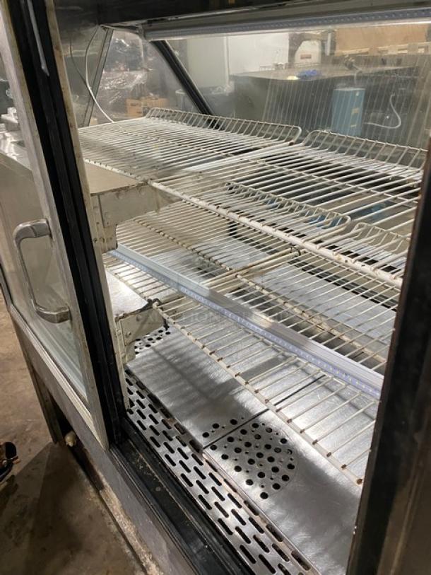Commercial stainless steel slanted glass bakery display case, multi-tier, poly coated wired rack, rear sliding glass door.