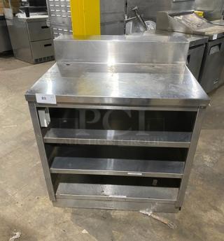 Commercial stainless steel enclosed cabinet table with multi-tier shelving, backsplash, rear shelving; good condition.