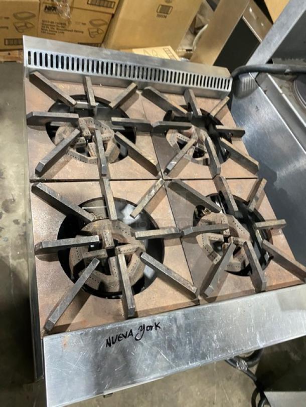 Jade Range Bistro Series 4-burner stainless steel natural gas range/oven combo. Includes wired oven rack, on legs, with visible wear.