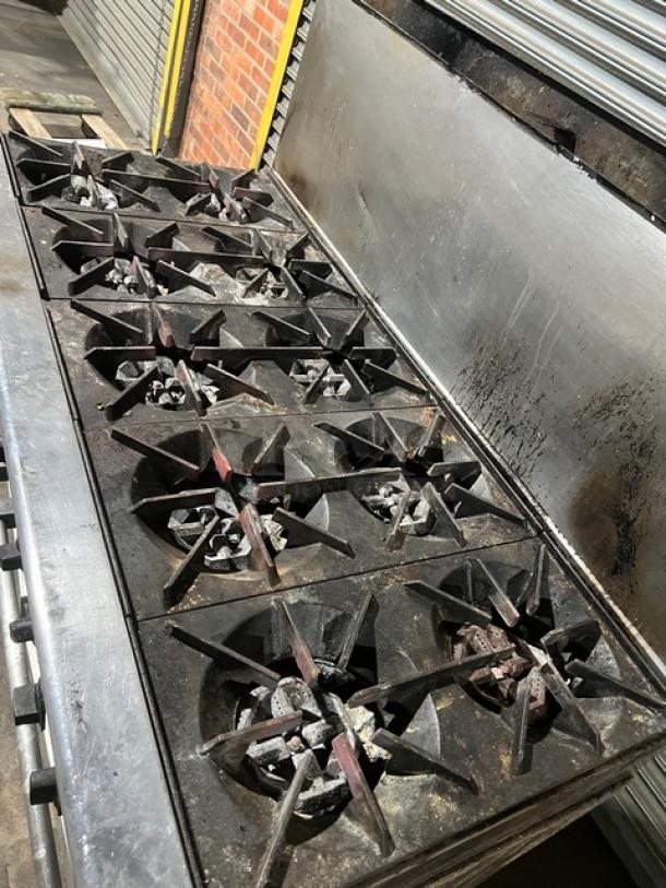 Commercial stainless steel gas 10-burner range by U.S. Range, with double oven, backsplash, and wired oven rack. Used condition.