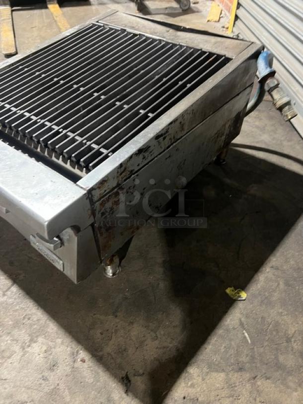 Garland commercial stainless steel gas-powered countertop char broiler on legs, showing slight wear, featuring robust grates.