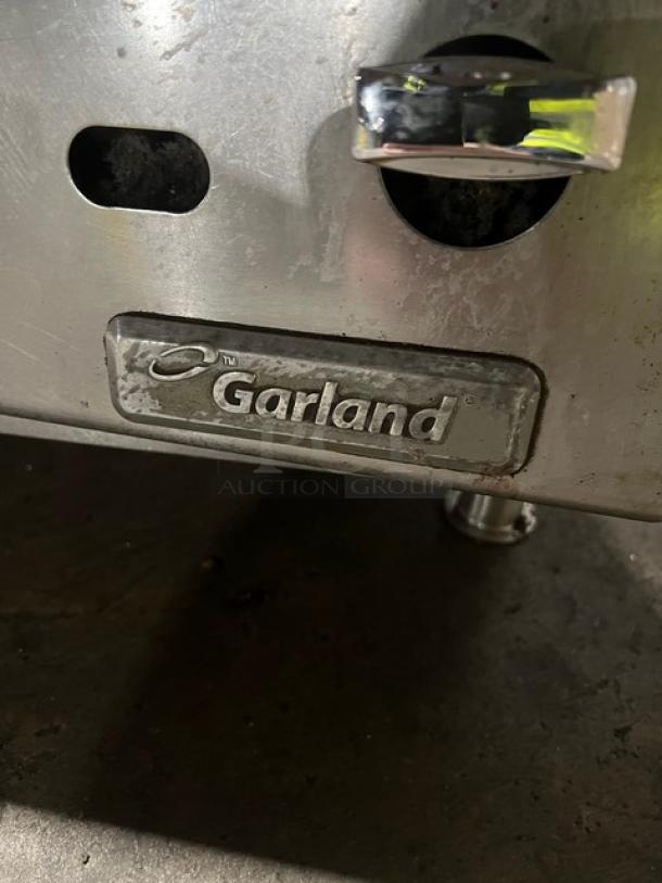 Garland stainless steel gas countertop char broiler, shown with control knobs and brand label, in used condition on sturdy legs.