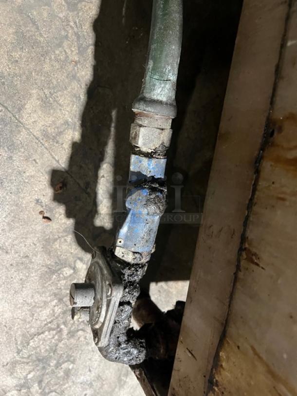 Garland commercial stainless steel gas countertop char broiler on legs; visible gas connection showing wear.