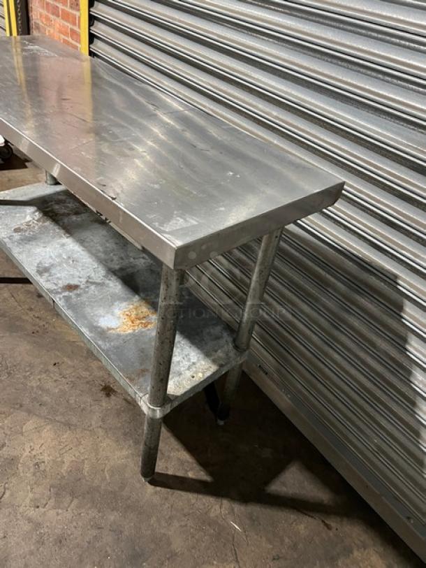 Commercial stainless steel worktop table with one undershelf, on legs. Some visible wear and rust on the shelf.