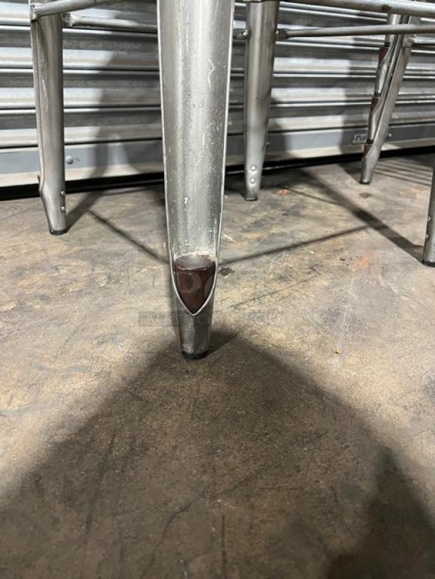 Stackable bar-height stool leg, metal finish, durable design, slight wear, ideal for commercial use.
