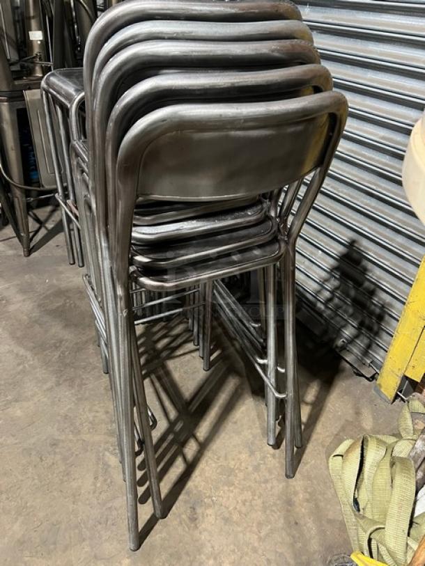 Stack of commercial stackable bar-height chairs, metal frame, industrial design, good condition, suitable for commercial use.