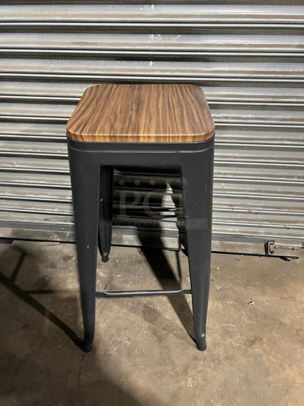 Commercial black stackable bar-height stool with wood seat, metal frame, excellent condition.