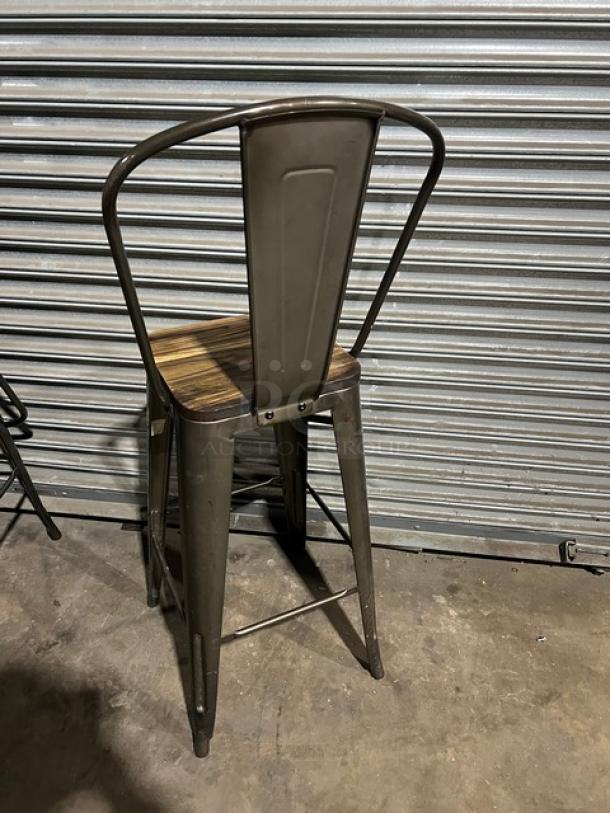 Industrial-style stackable bar-height chair with metal frame and wooden seat. Good condition, suitable for commercial use.