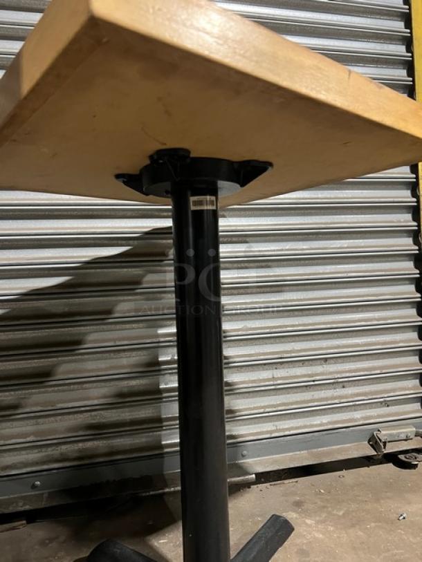 Commercial dining-height table with a wooden top and black metal pedestal base. In good condition, ideal for restaurants.