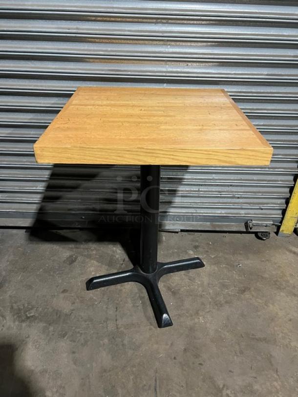 Commercial dining-height table with a square wooden top and black metal pedestal base. Excellent condition.