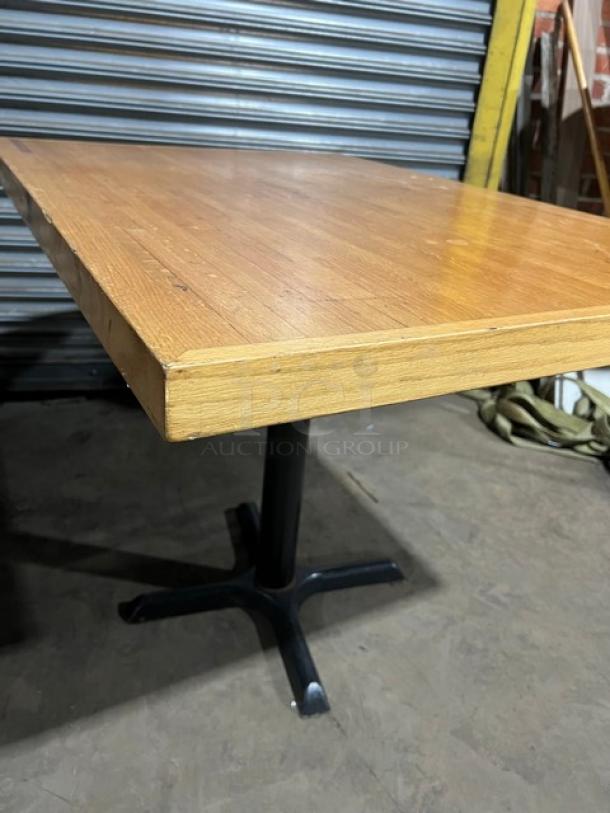 Commercial wooden rectangular tabletop with a black pedestal base, in good condition. Ideal for dining or cafe settings.
