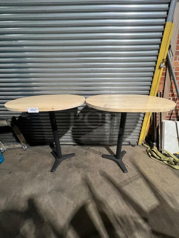 Commercial wooden oval tabletops with pedestal bases, two units shown. Sturdy condition, ideal for dining or business use.
