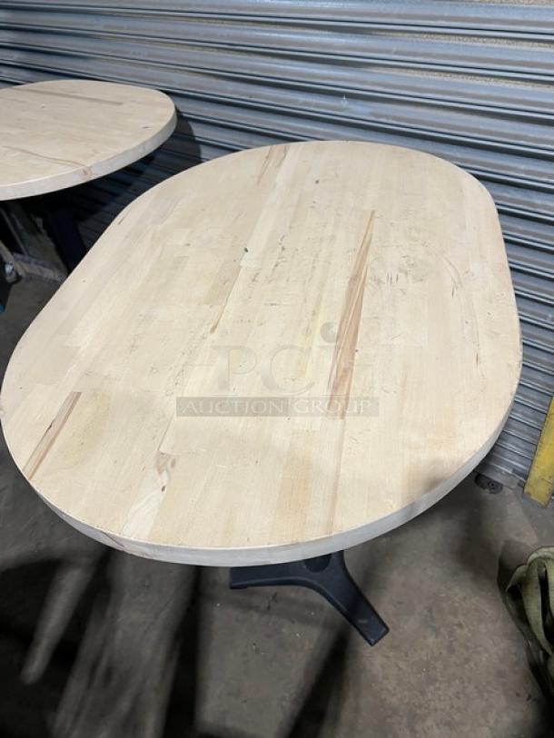 Commercial wooden oval tabletop with pedestal base, light wood finish. Good condition, suitable for restaurant use.