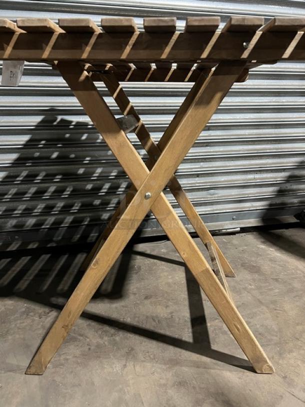 Wooden folding table with slatted top and X-frame legs. Commercial use, sturdy build, natural finish, in good condition.