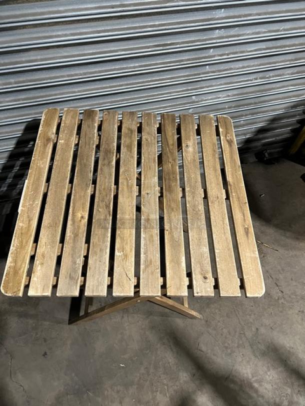 Commercial wooden folding table, slatted top, natural finish, good condition, sturdy design, suitable for various uses.