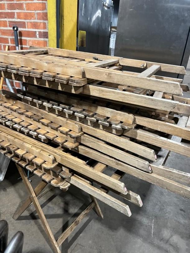 Commercial wooden folding tables, stacked. Features sturdy wood construction. Suitable for events. Used condition.