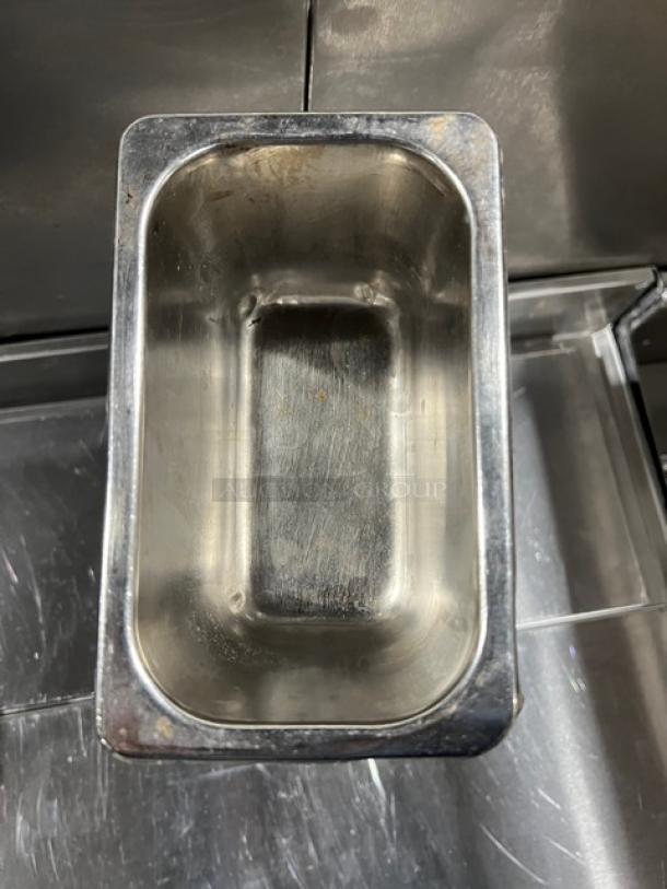 Stainless steel hotel steamtable pan, rectangular, showing signs of use, ideal for commercial kitchen settings.